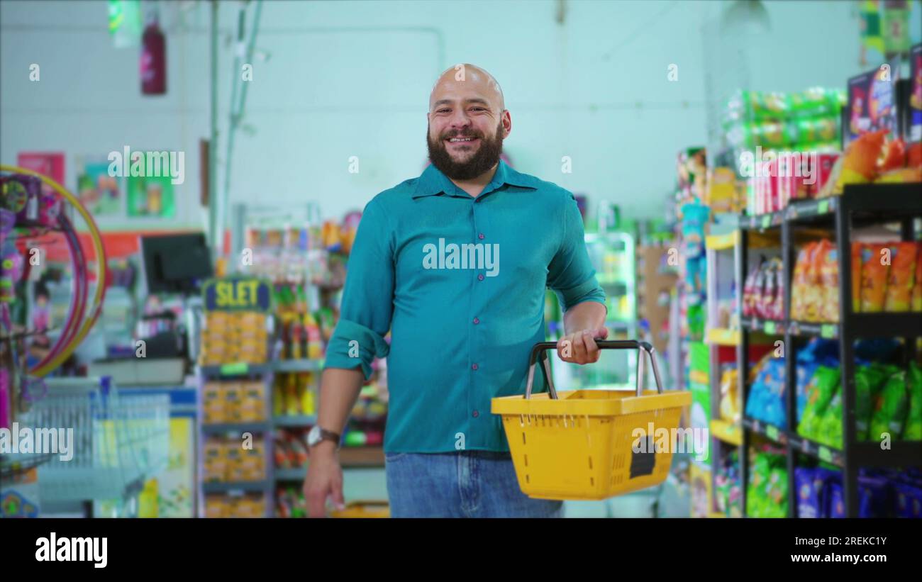 Happy Brazilian man standing at Grocery Store holding basket in hand ...