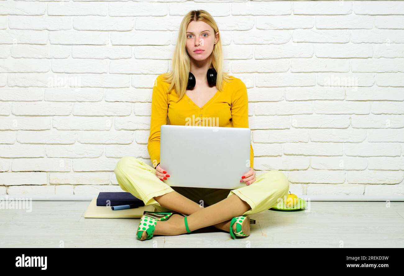 E-learning. Serious female student sitting on floor with legs crossed studying online at home. High school. University student girl preparing for test Stock Photo