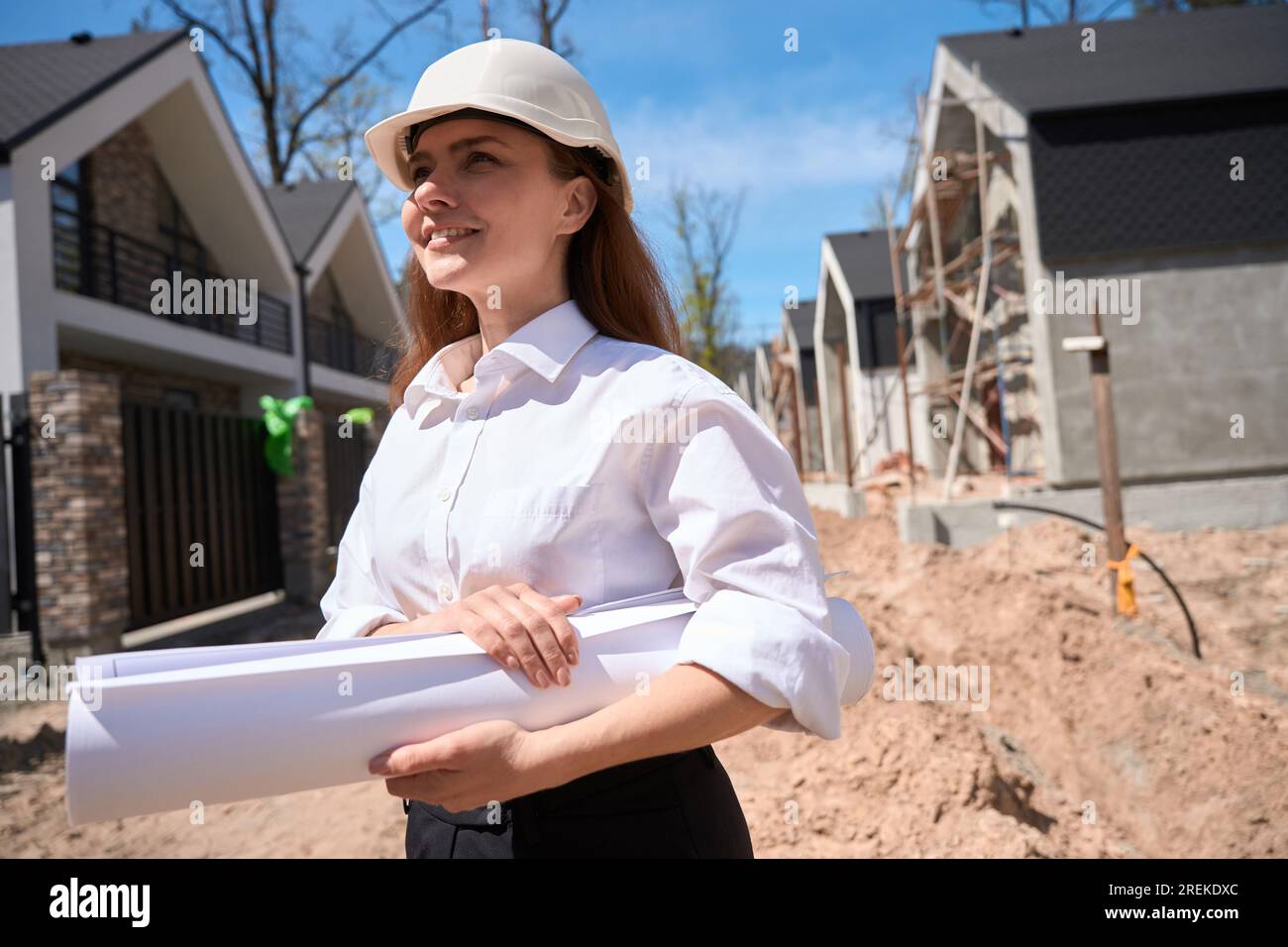 Woman general architect in hardhat coming to construction site with blueprints Stock Photo