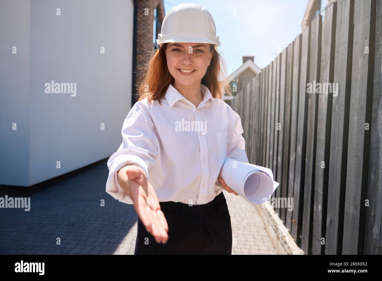 Woman architect in hardhat welcoming contractor, reaching out hand to shake Stock Photo