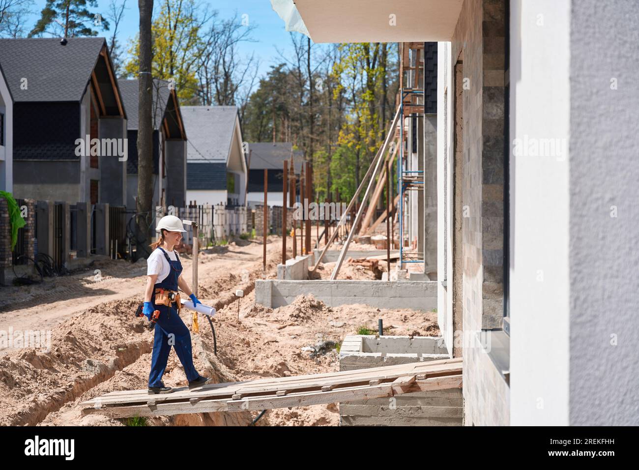 Forewoman going to house under construction holding electric screwdriver Stock Photo