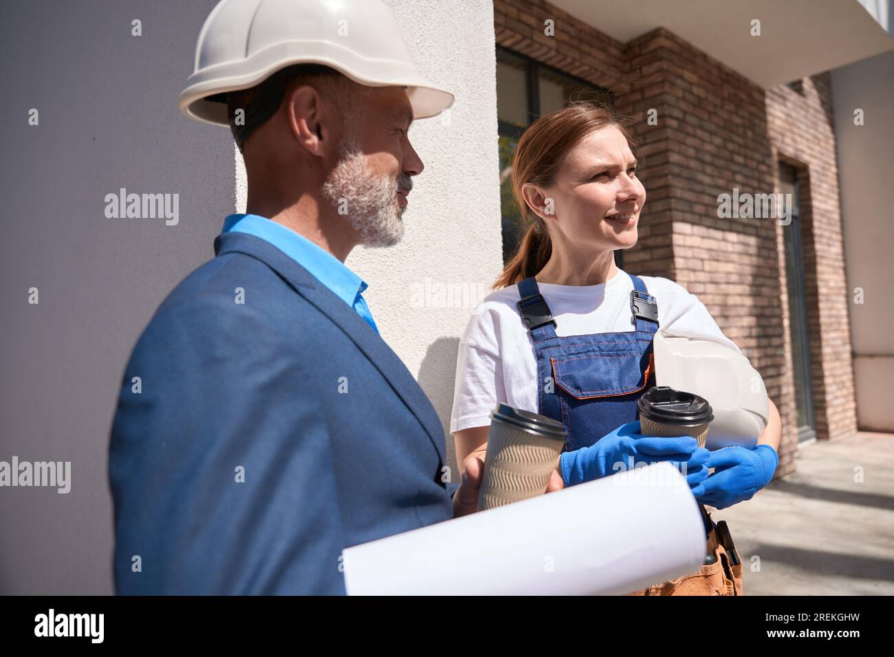 Colleagues drinking coffee during break and discussing construction site project Stock Photo