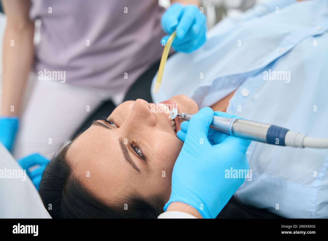 Qualified stomatologist smoothing uneven edges of patient tooth after
