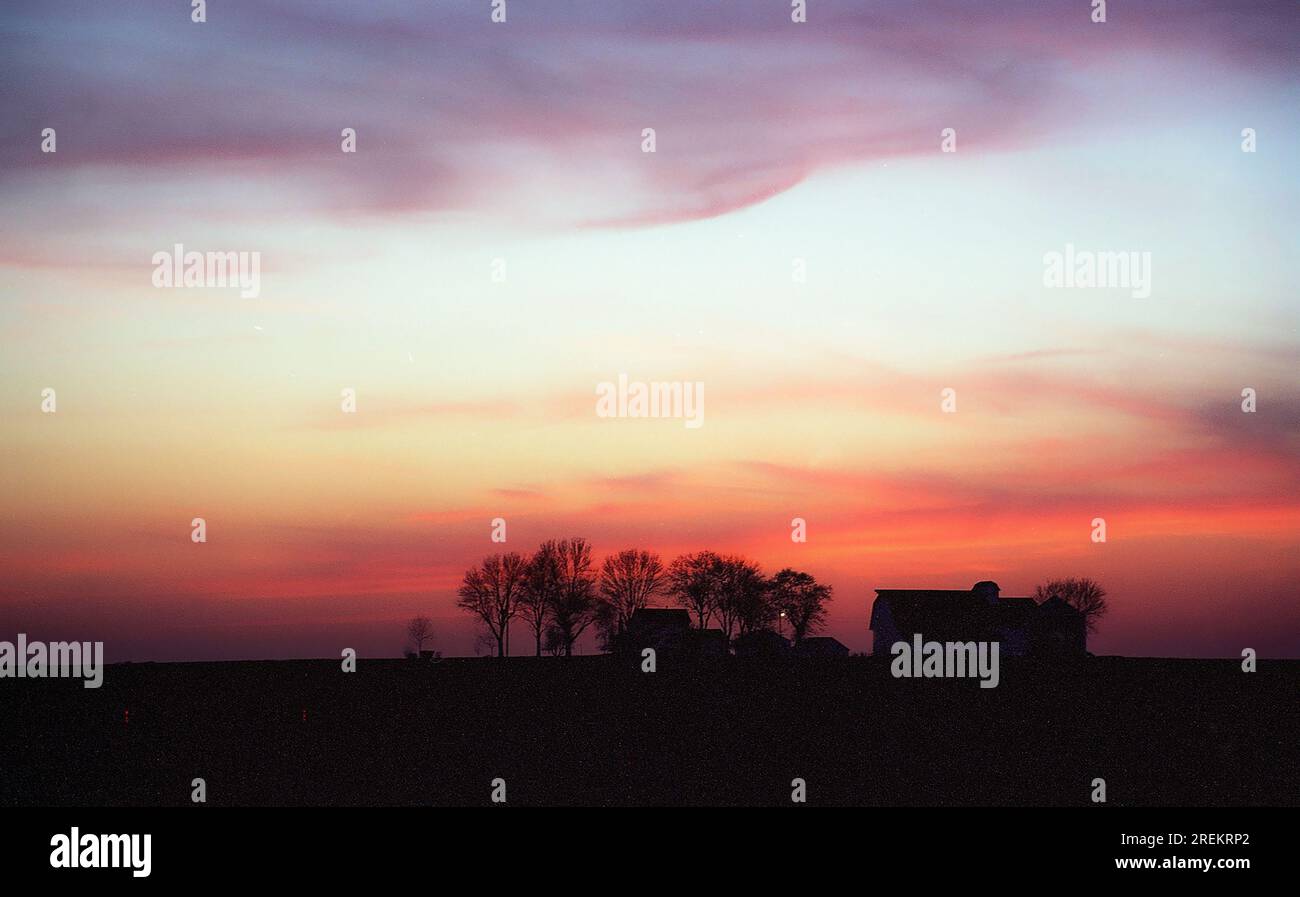 silhouette of a farm against a red sunset sky Stock Photo