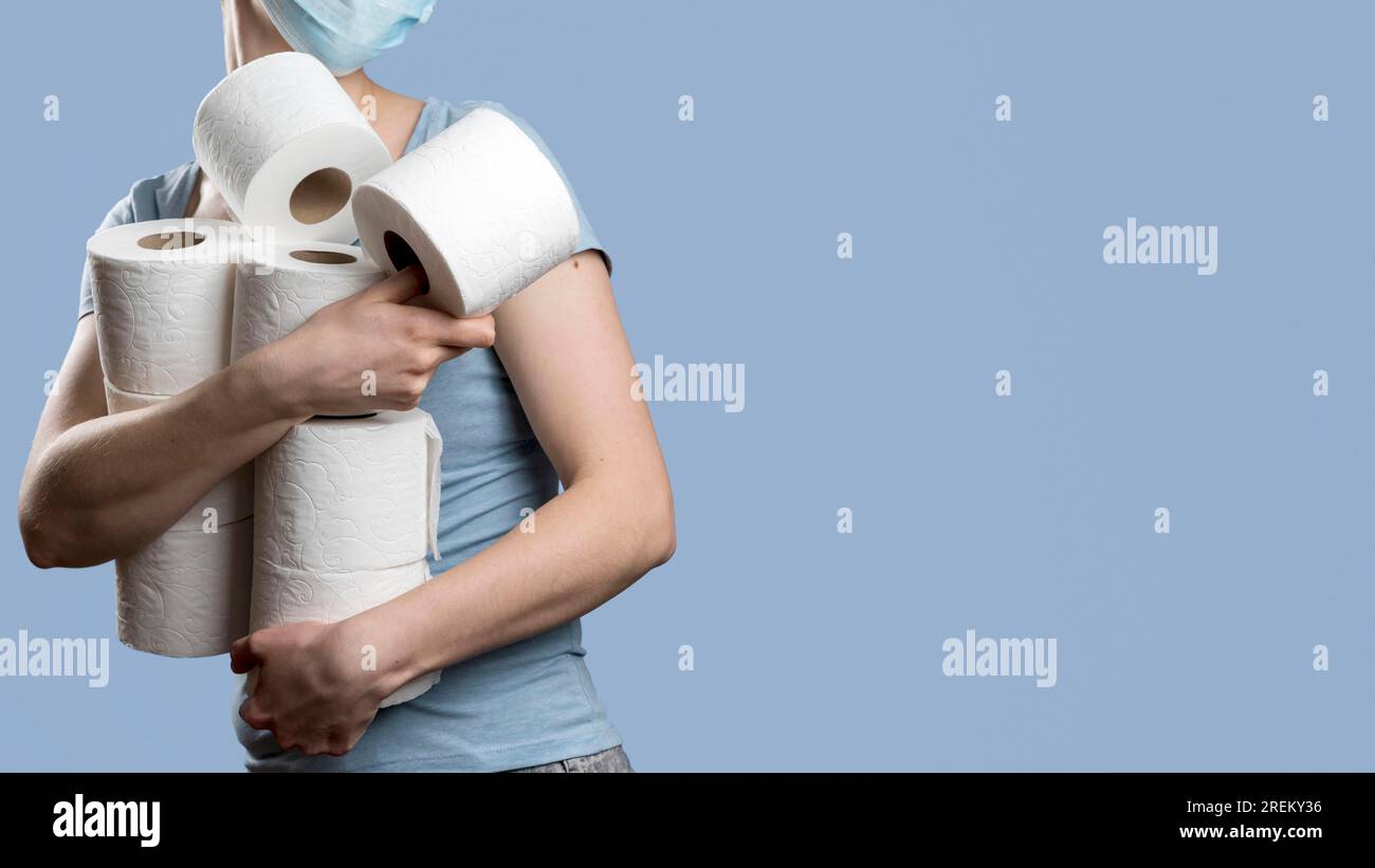 Side view woman holding many toilet paper rolls while wearing medical mask.  High resolution photo Stock Photo - Alamy