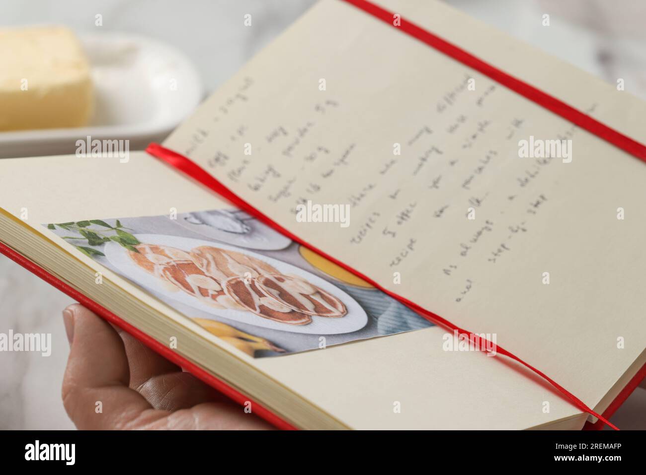 Man with recipe book at table in kitchen, closeup Stock Photo