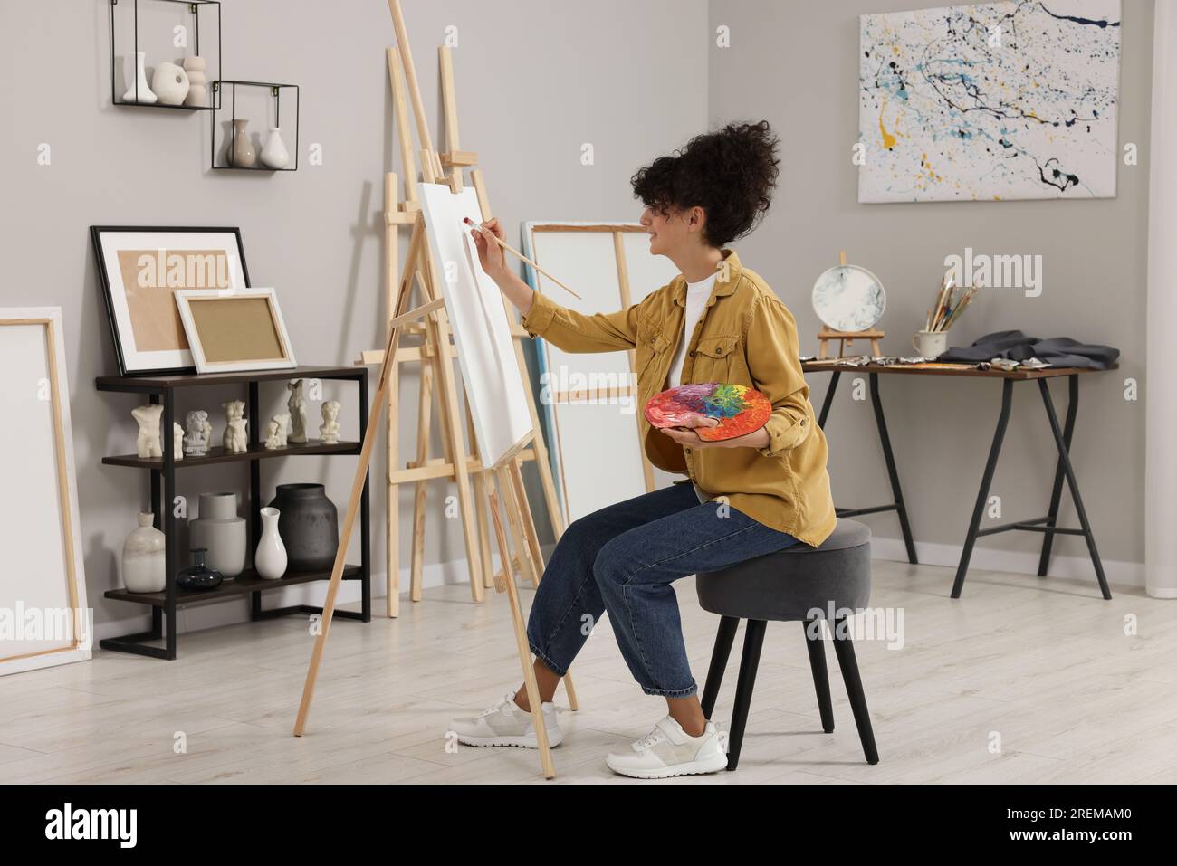 Young woman painting on easel with canvas in studio Stock Photo - Alamy