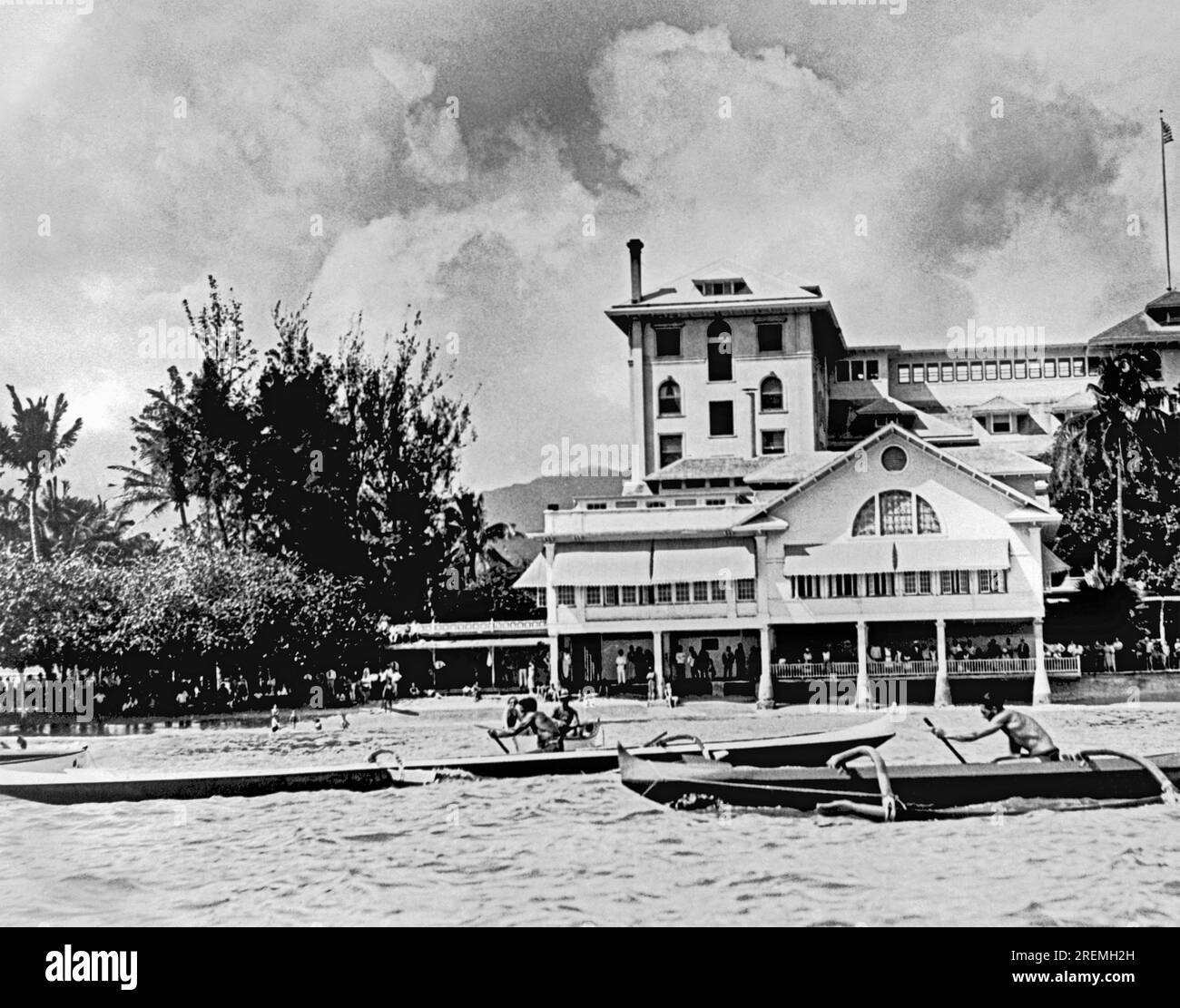 Honolulu, Hawaii    c 1928 Swimming star Duke Kahanamoku wins the one man canoe championship in his long black and white outrigger, crossing the finish line in front of the Moana Hotel on Waikiki beach. Stock Photo