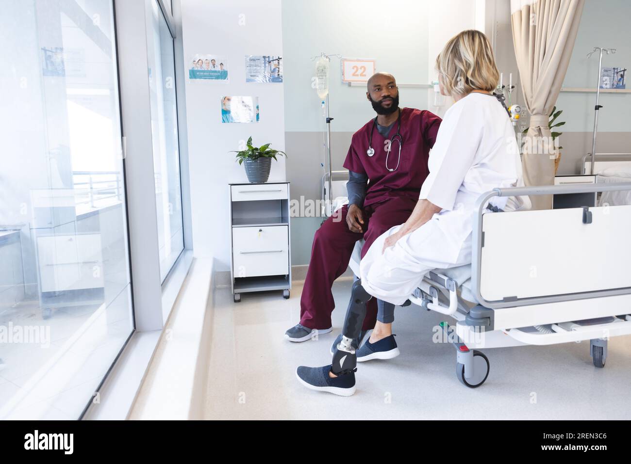 African american male doctor talking to senior caucasian patient with prosthetic leg at hospital Stock Photo