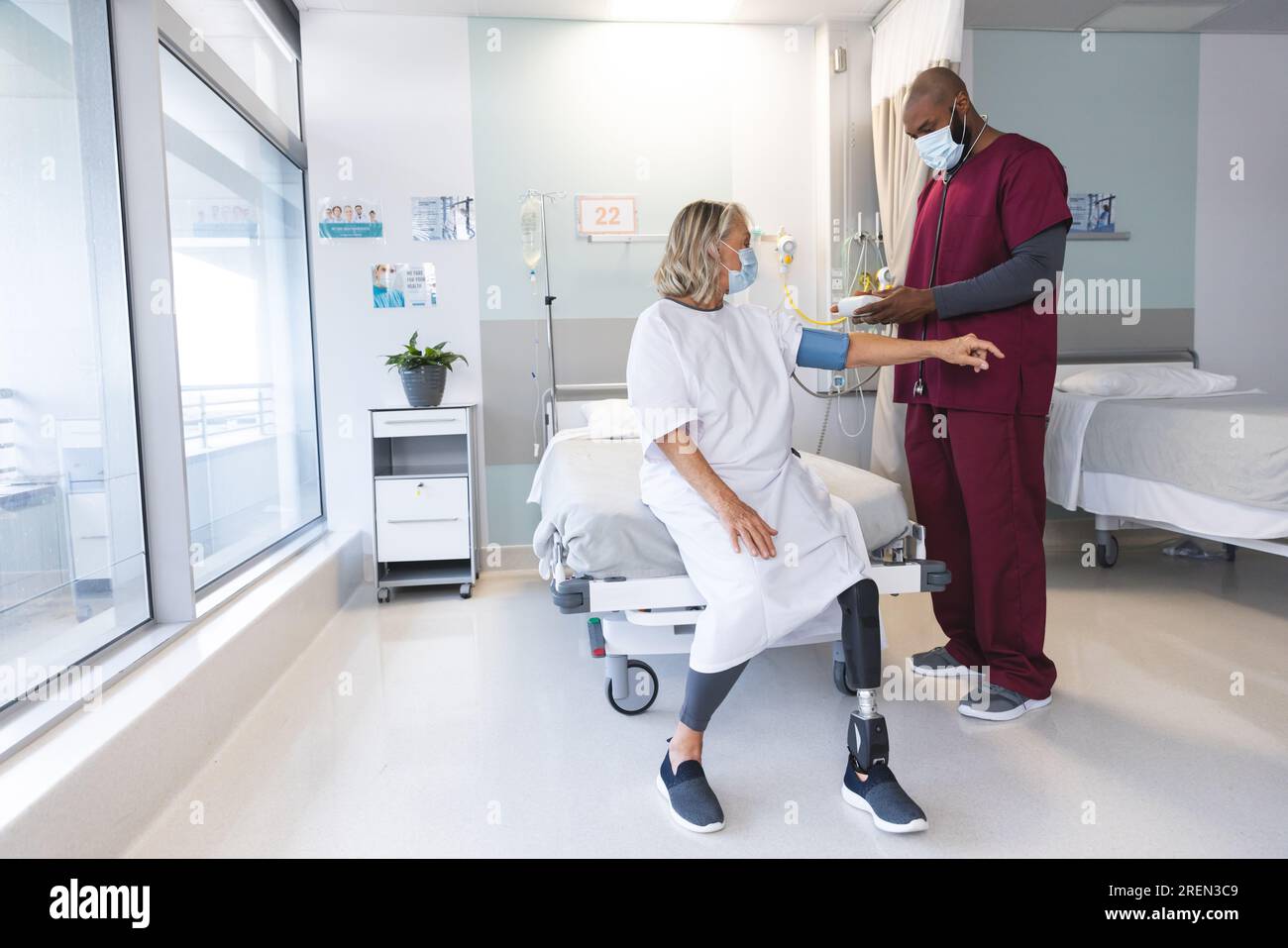African american doctor measuring blood pressure of senior caucasian patient with prosthetic leg Stock Photo