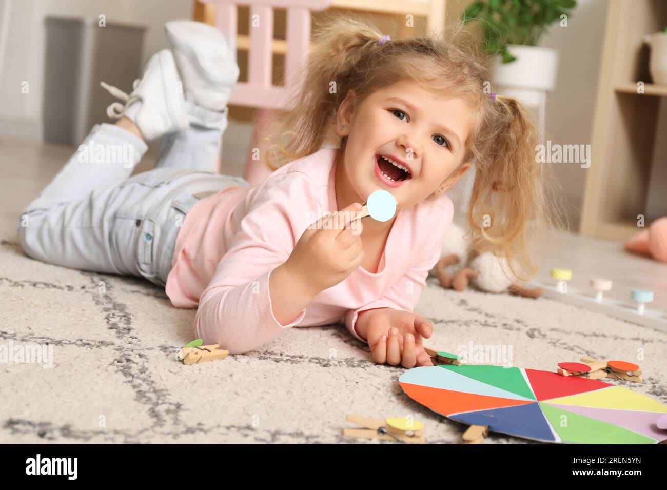 Cute little girl playing matching game with clothespins on floor at home Stock Photo Alamy