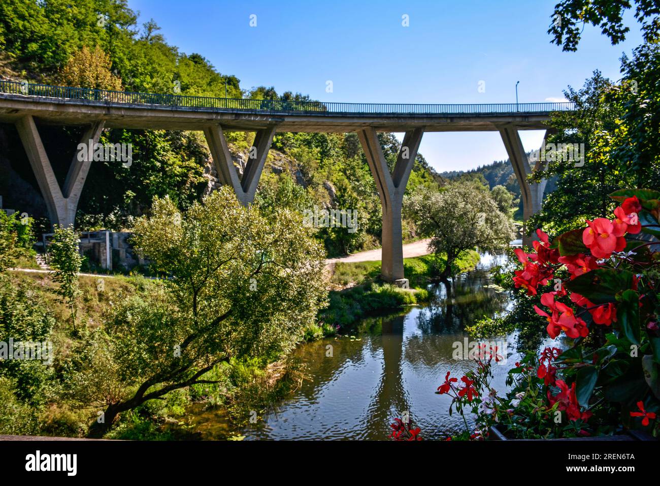 Red Flowers, River and Bridge at Rastoke Village - Croatia Stock Photo