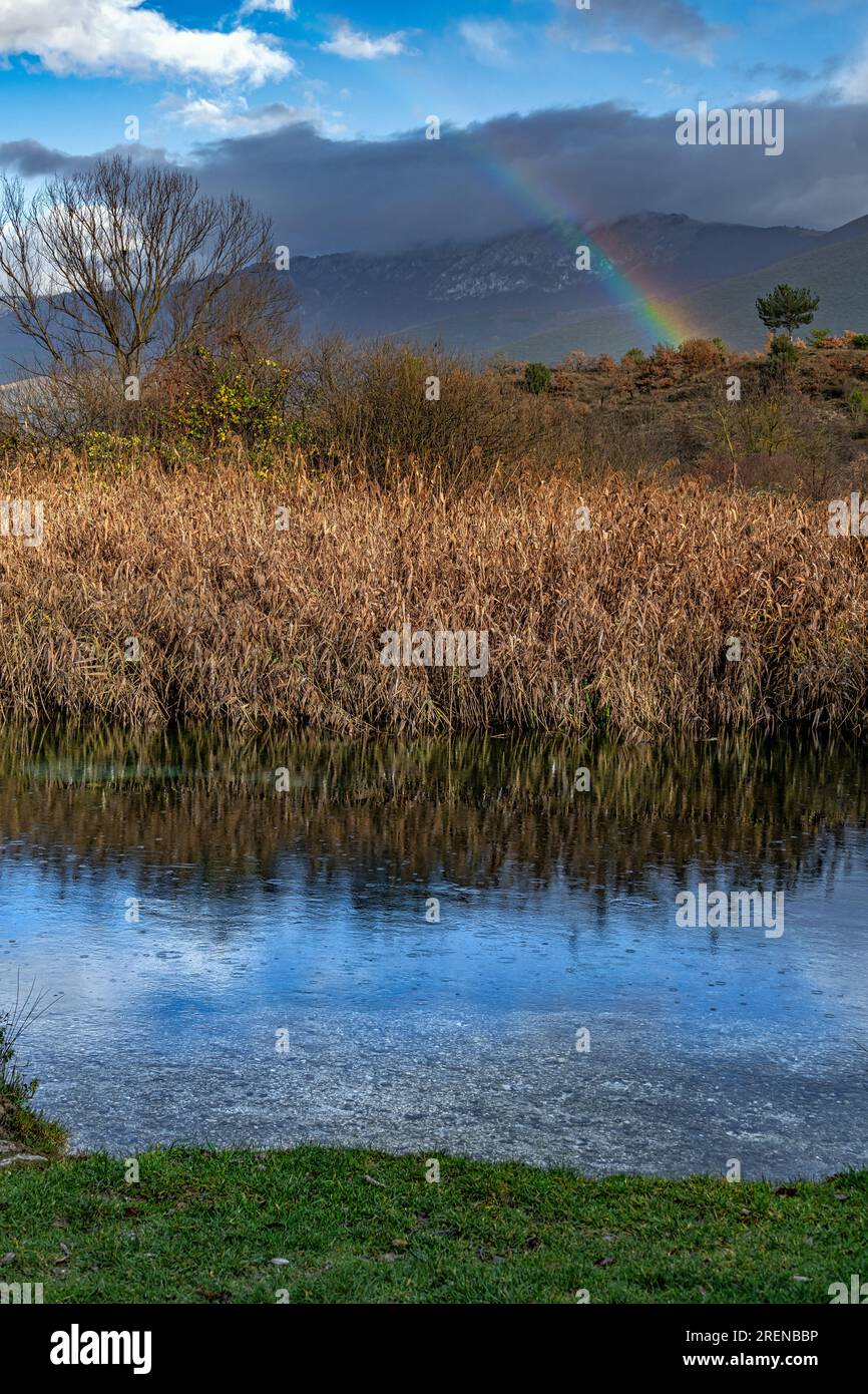The transparent waters of the Tirino river mirror the rainbow after a storm. Abruzzo, Italy Stock Photo