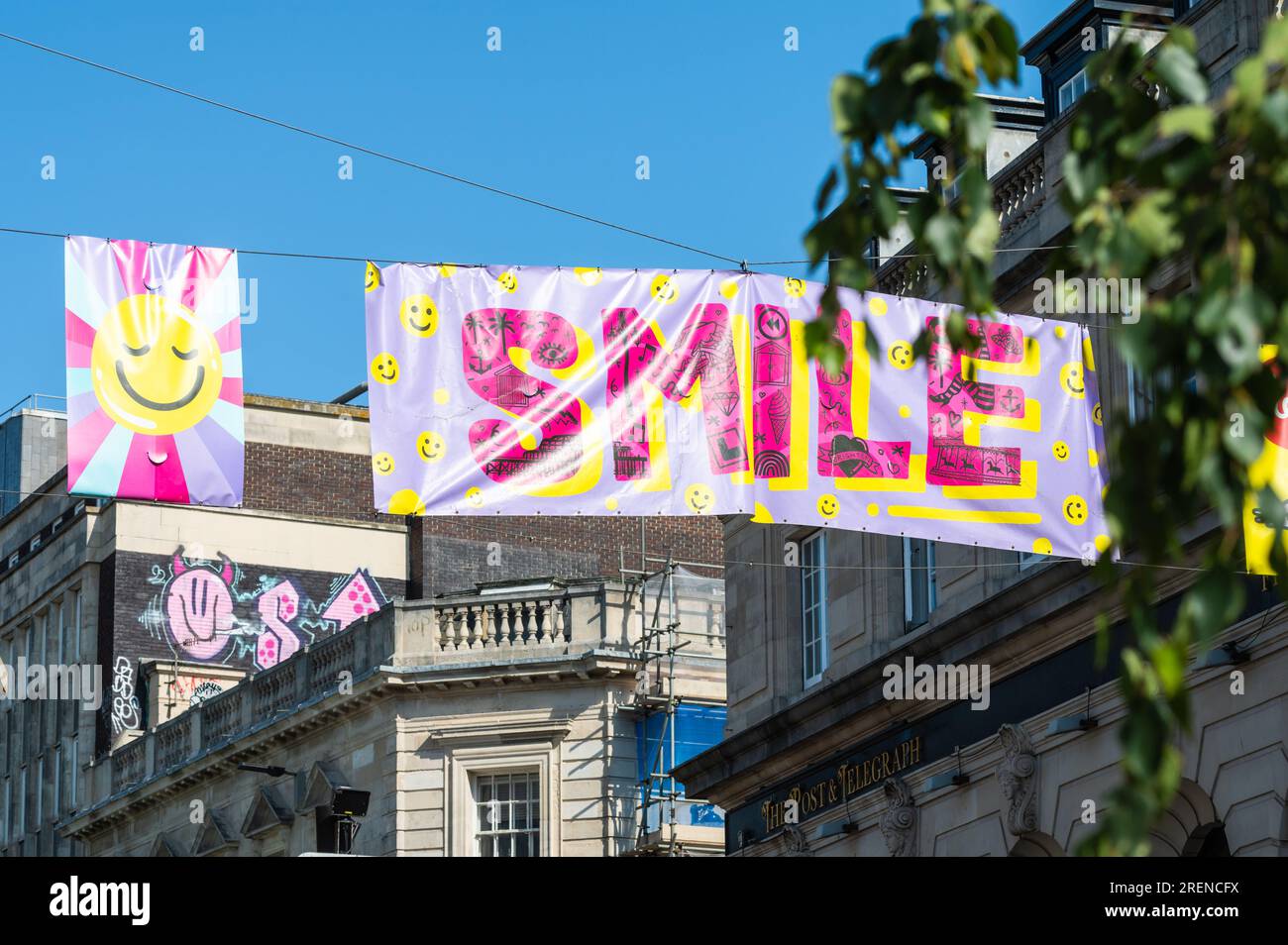 Colourful smile banner hanging across North Street in Brighton town centre, in Summer, in the City of Brighton & Hove, East Sussex, England, UK. Stock Photo