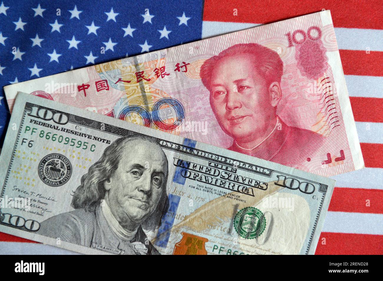 China. 29th July, 2023. In this photo illustration, a 100 RMB and a 100 USD  currency cash are displayed on a table with the American flag in the  background. Credit: SOPA Images