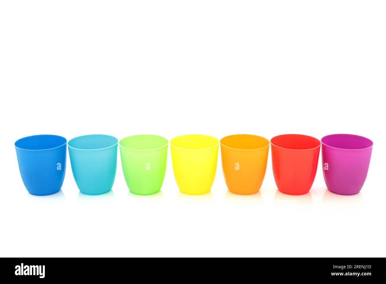 Rainbow drinking cups in a line on white background. Minimal colorful