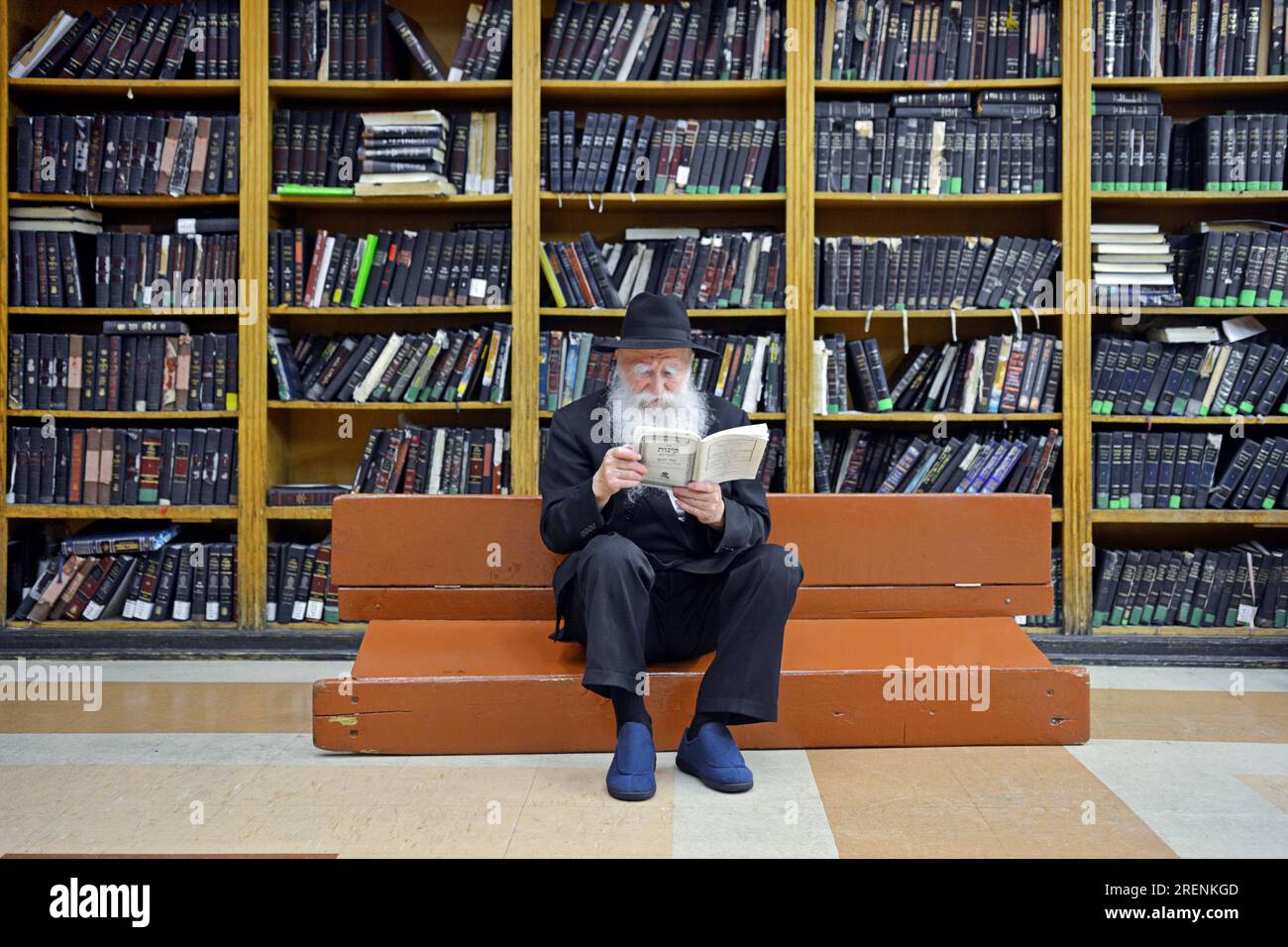 Chabad rabbi sits on an overturned bench and wears plastic shoes on Tisha B'av following the mourning rituals of the saddest day of the Jewish year. Stock Photo