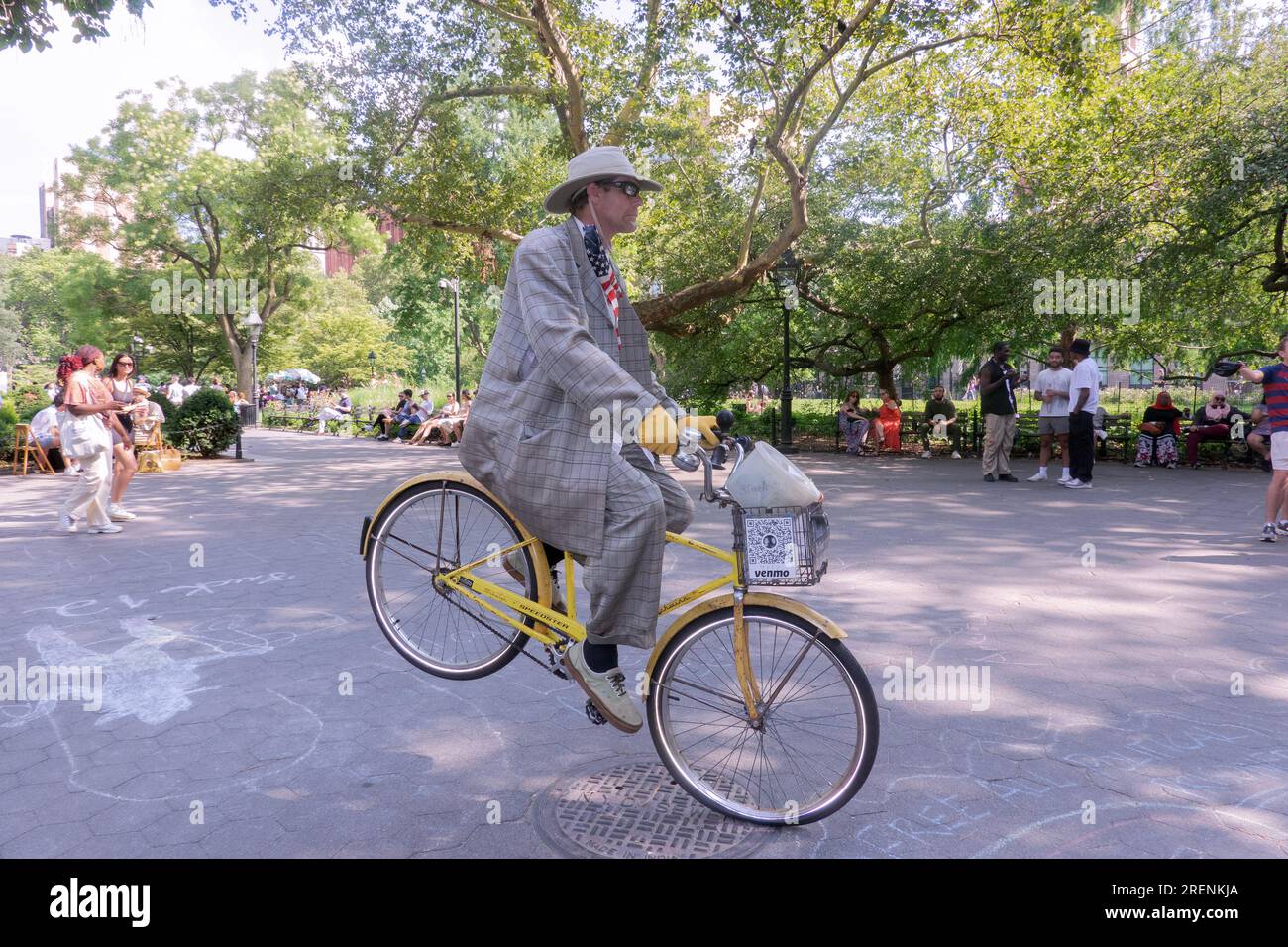 A busker on a bike appears to be violating gravity. In Washington Square Park in Greenwich Village, New York City. Stock Photo