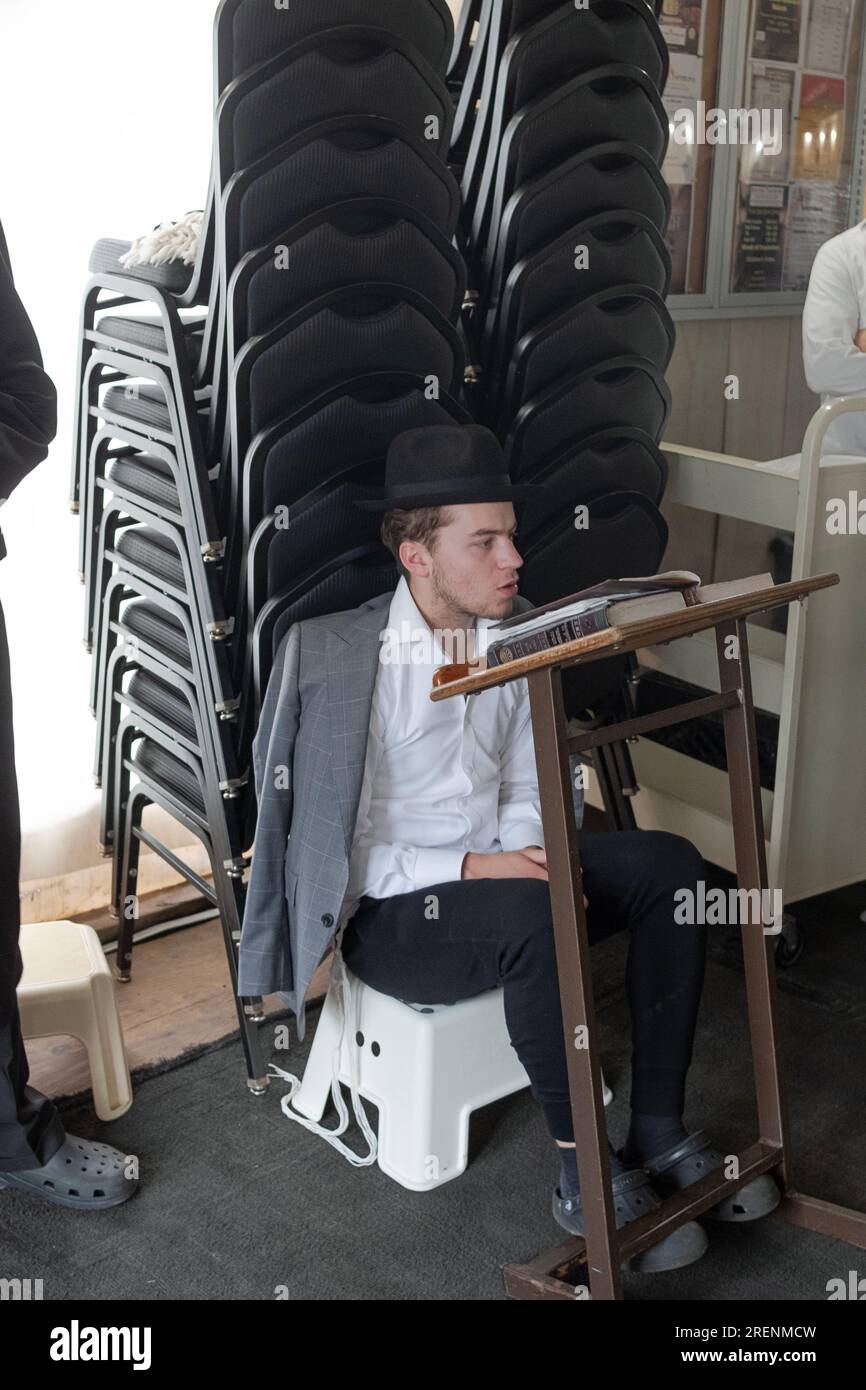 At Tisha B'Av services a young man observes the mourning aspects of the day by fasting, sitting on a low seat & not wearing leather shoes. In Rockland. Stock Photo