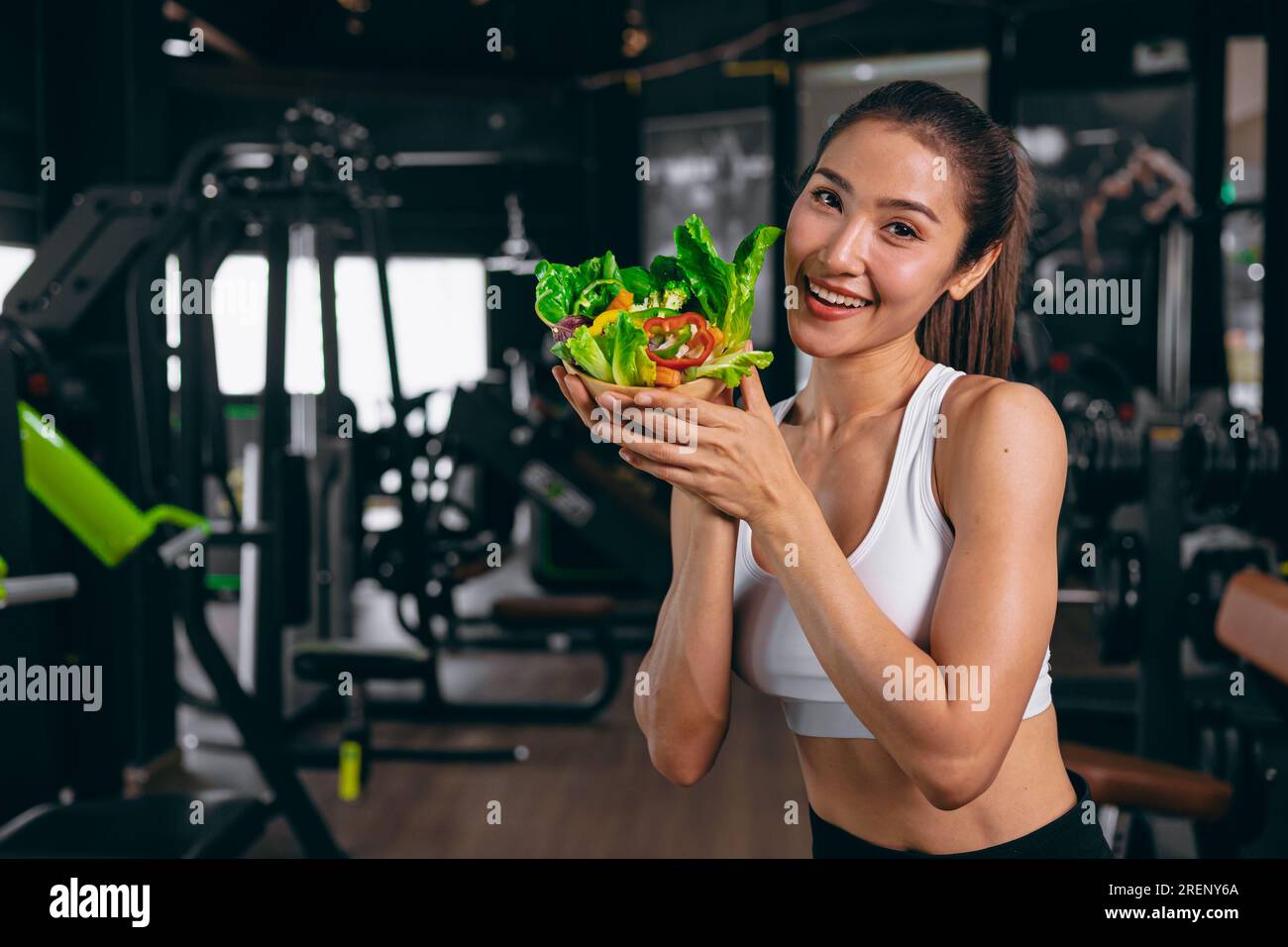 sport healthy beautiful asian woman showing vegetables mix salad for diet food low calories in fitness sport club Stock Photo