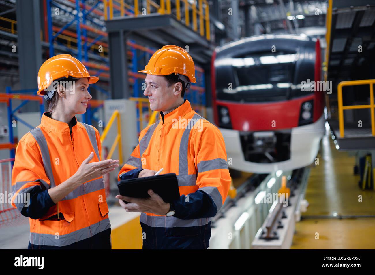 Engineer man and women worker working team together in electric train service depot transport industry factory technician mechanic staff. Stock Photo