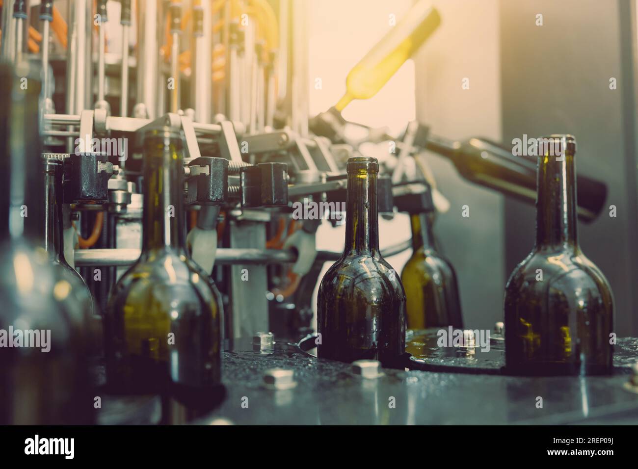 dark wine bottle water injection cleaning machine closeup in operation in winery factory Stock Photo
