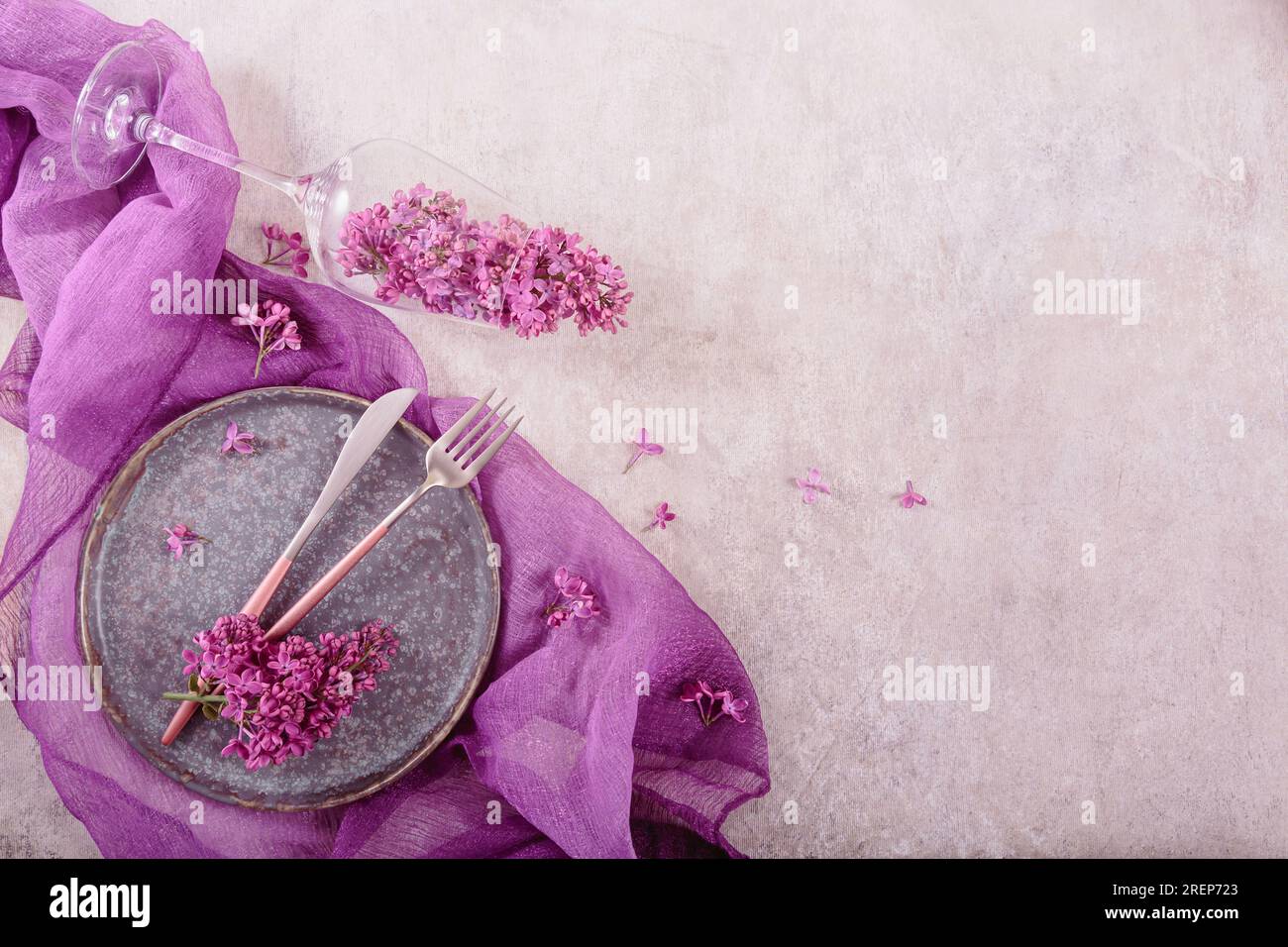 Table setting with drinking glass full of lilac flowers Stock Photo