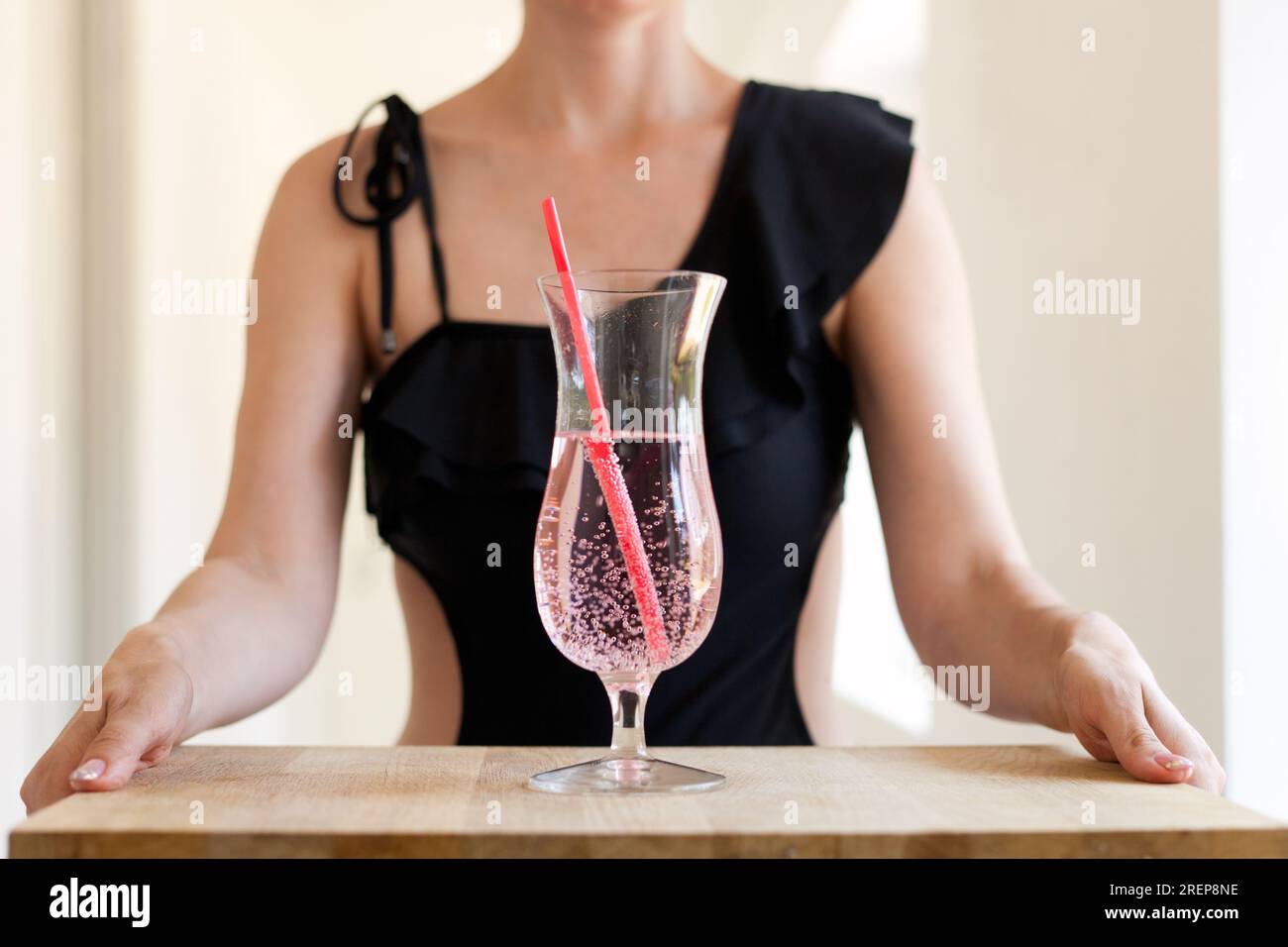 woman in swimsuit holding coctail glass with straw at table. Fruit lemonade healthy drinking beverage Close Stock Photo