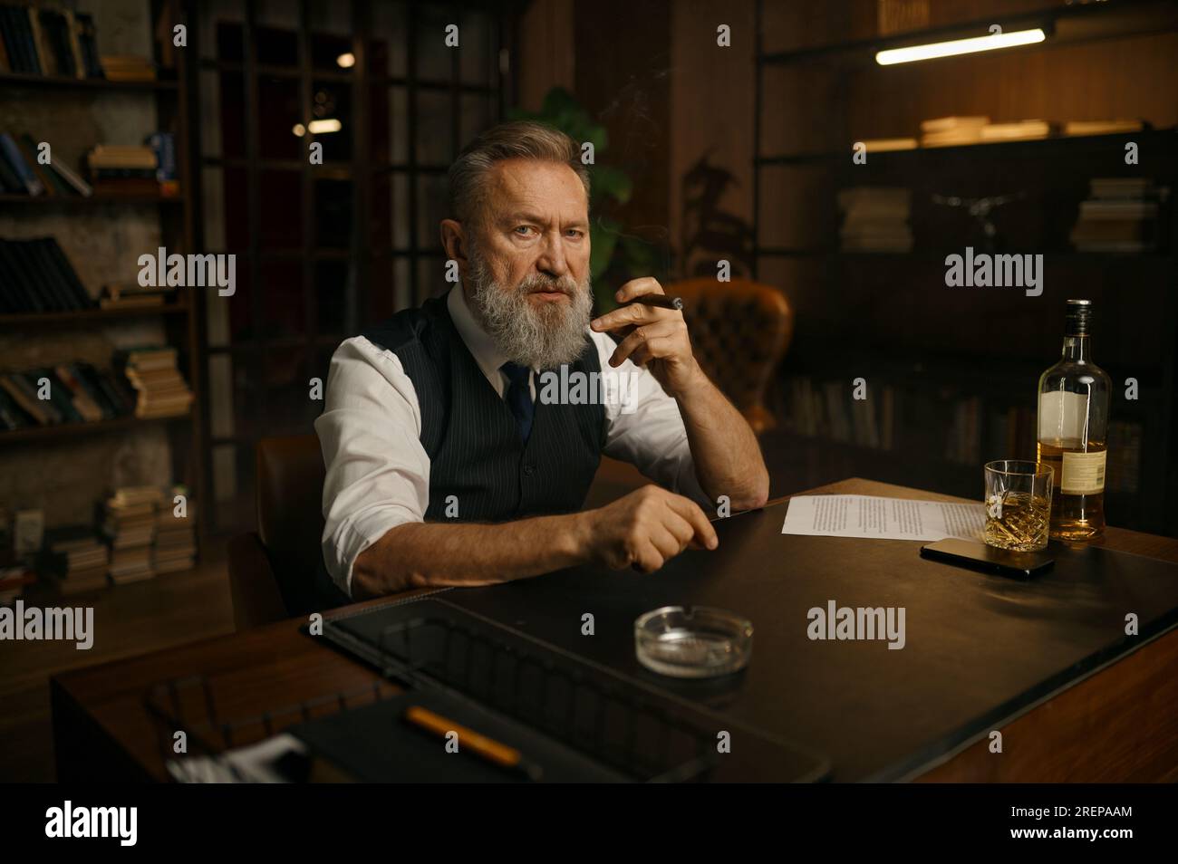 Pensive senior business man smoking cigar while sitting at work table ...