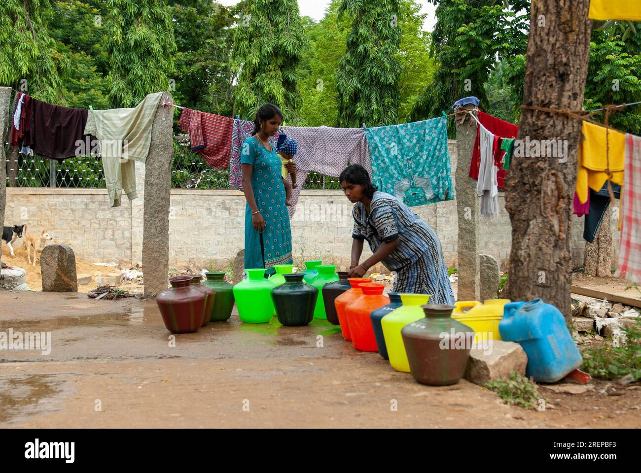 Bangalore, India - August 6, 2011: Ladies with plastic containers filled with water point to a lack of potable drinking water in Bangalore, India on A Stock Photo