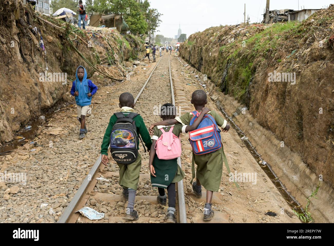 KENYA, Nairobi, Kibera slum, pupils with tornister walking from school to home on Kibera railway track / KENIA, Nairobi, Slum Kibera, Kinder gehen nach der Schule nach Hause an der Kibera Bahnlinie Stock Photo