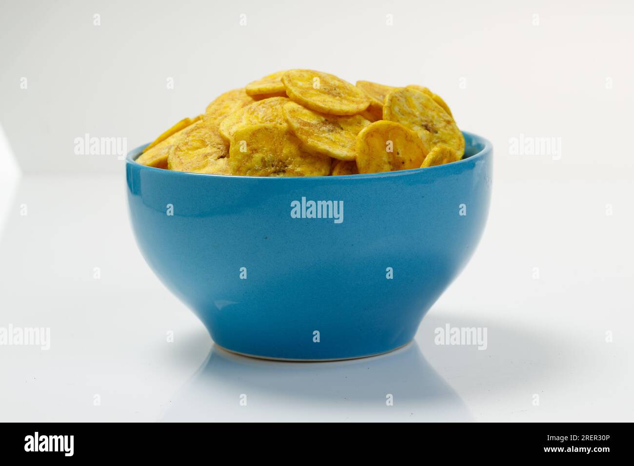 Kerala chips or Banana chips, cult snack item of Kerala,arranged in a pastle colour ceramic bowl,Isolated image with white background Stock Photo