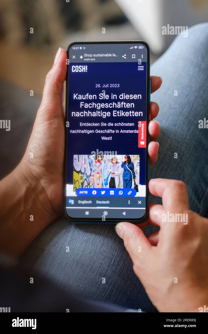 Woman holding smartphone showing the website of cosh.eco's sustainability platform. Stock Photo
