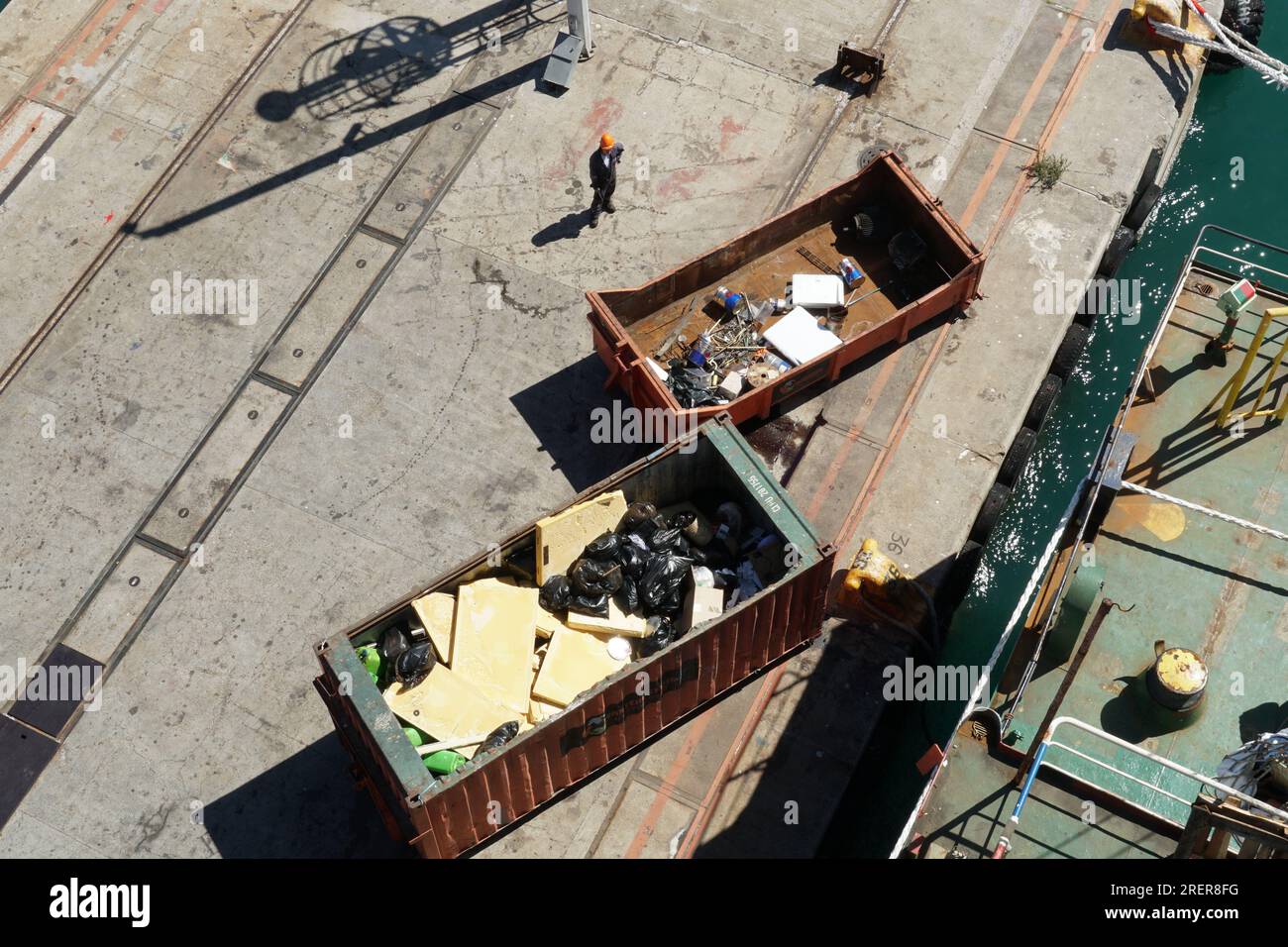 Two orange open top containers full of garbage in black plastic bags