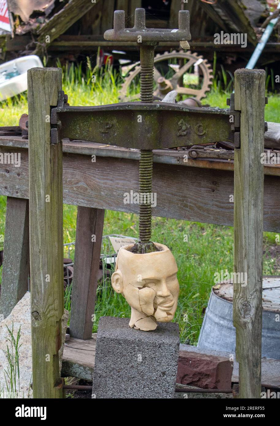whimsical sculpture of a head being crushed in a old vise Stock Photo