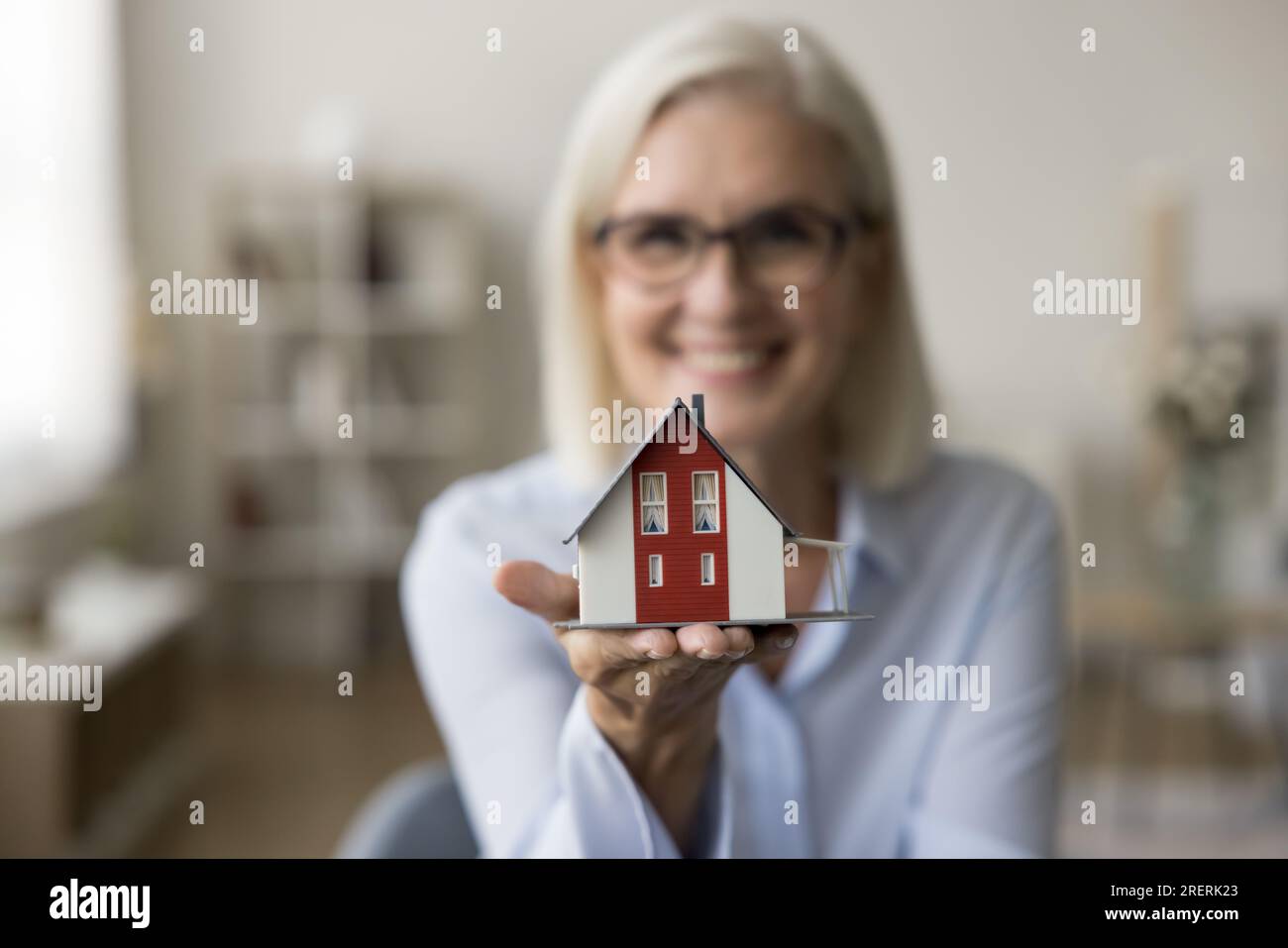 Tiny house model on hand of real estate agent woman Stock Photo - Alamy