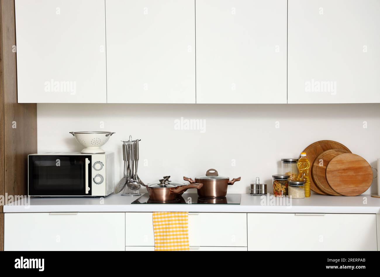 Interior of modern kitchen with white counters, microwave oven and ...