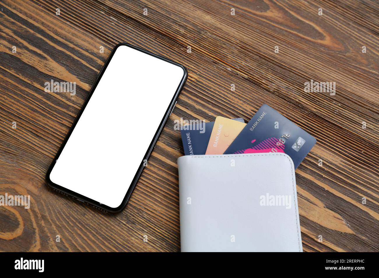 Mobile phone with wallet and credit cards on brown wooden background Stock Photo