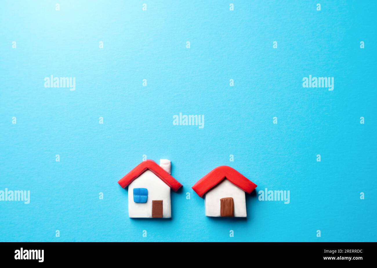 Two houses on a blue background. Place for text. Find most suitable housing options. Mortgage. Valuation of residential buildings. Realtor services. B Stock Photo