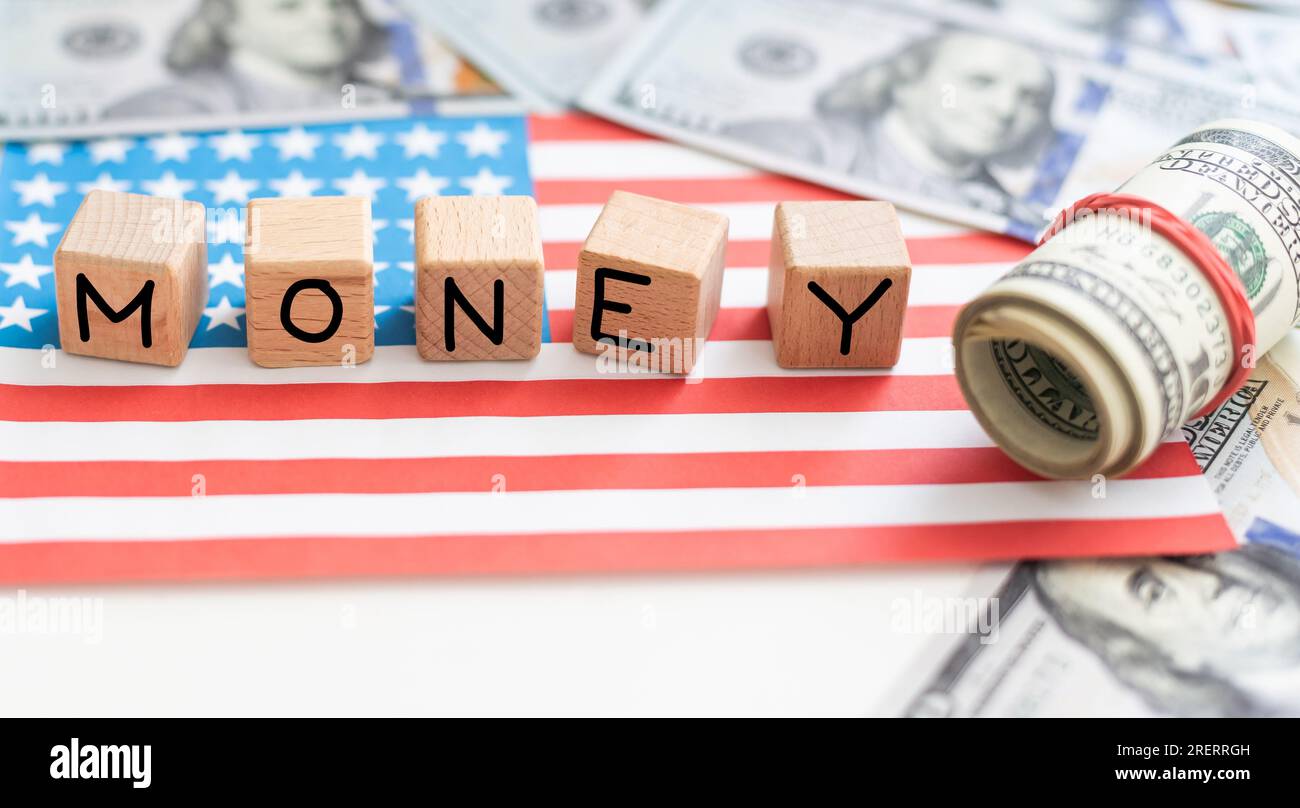 Word MONEY written by wooden cubes with american flag and american dollar bills. Stock Photo