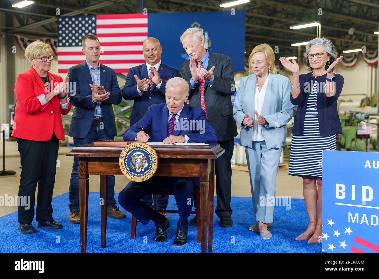 Auburn, United States of America. 28 July, 2023. U.S President Joe Biden surrounded by members of Congress signs an Executive Order to encourage companies to manufacture new inventions in the United States at Auburn Manufacturing Inc textile mill, July 28, 2023 in Auburn, Maine, USA. Left to right Rep. Chellie Pingree, Rep. Jared Golden, Auburn Mayor Jason Levesque, Sen. Angus King, Maine Gov. Janet Mills, and Kathie Leonard, CEO of Auburn Manufacturing. Credit: Adam Schultz/White House Photo/Alamy Live News Stock Photo