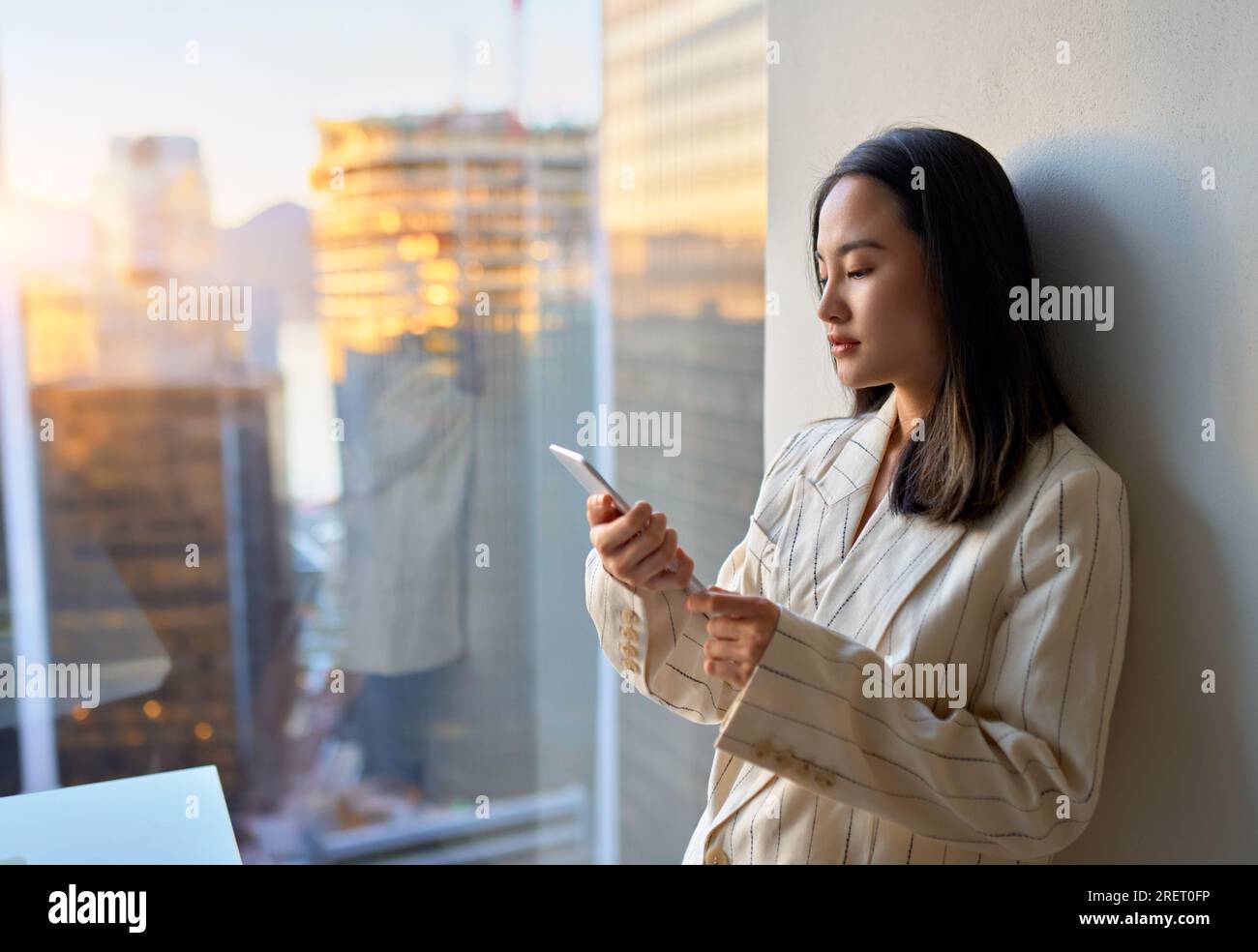 Young Asian business woman executive using tablet standing in office at window. Stock Photo
