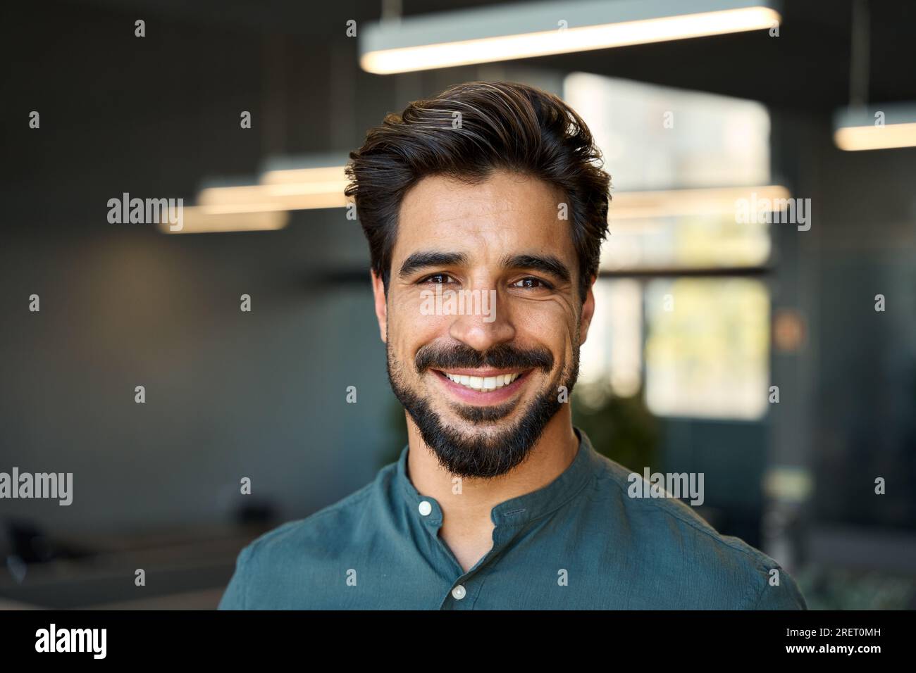 Happy handsome young business man looking at camera in office headshot portrait. Stock Photo