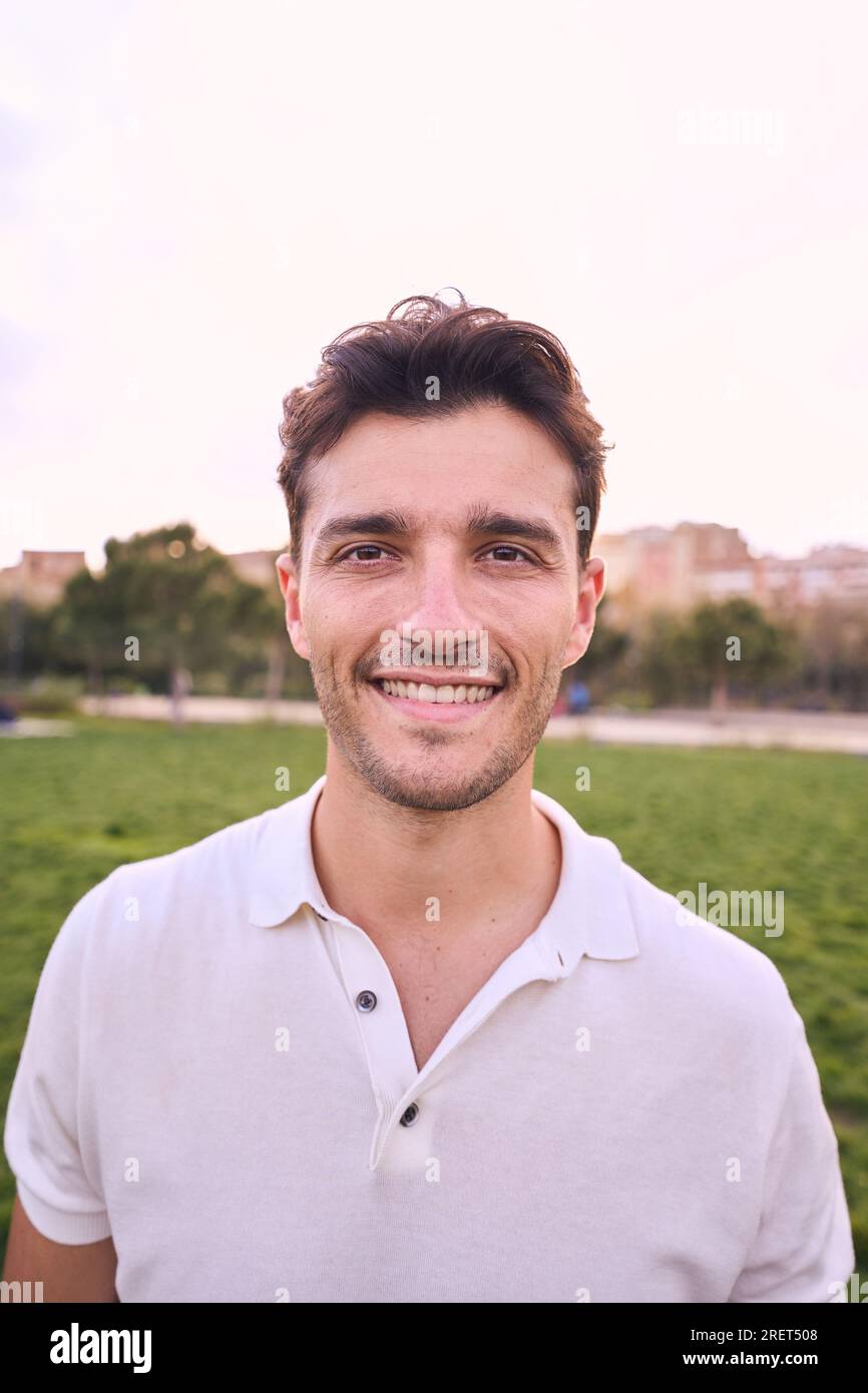 Vertical portrait of attractive smiling young man looking at camera in ...