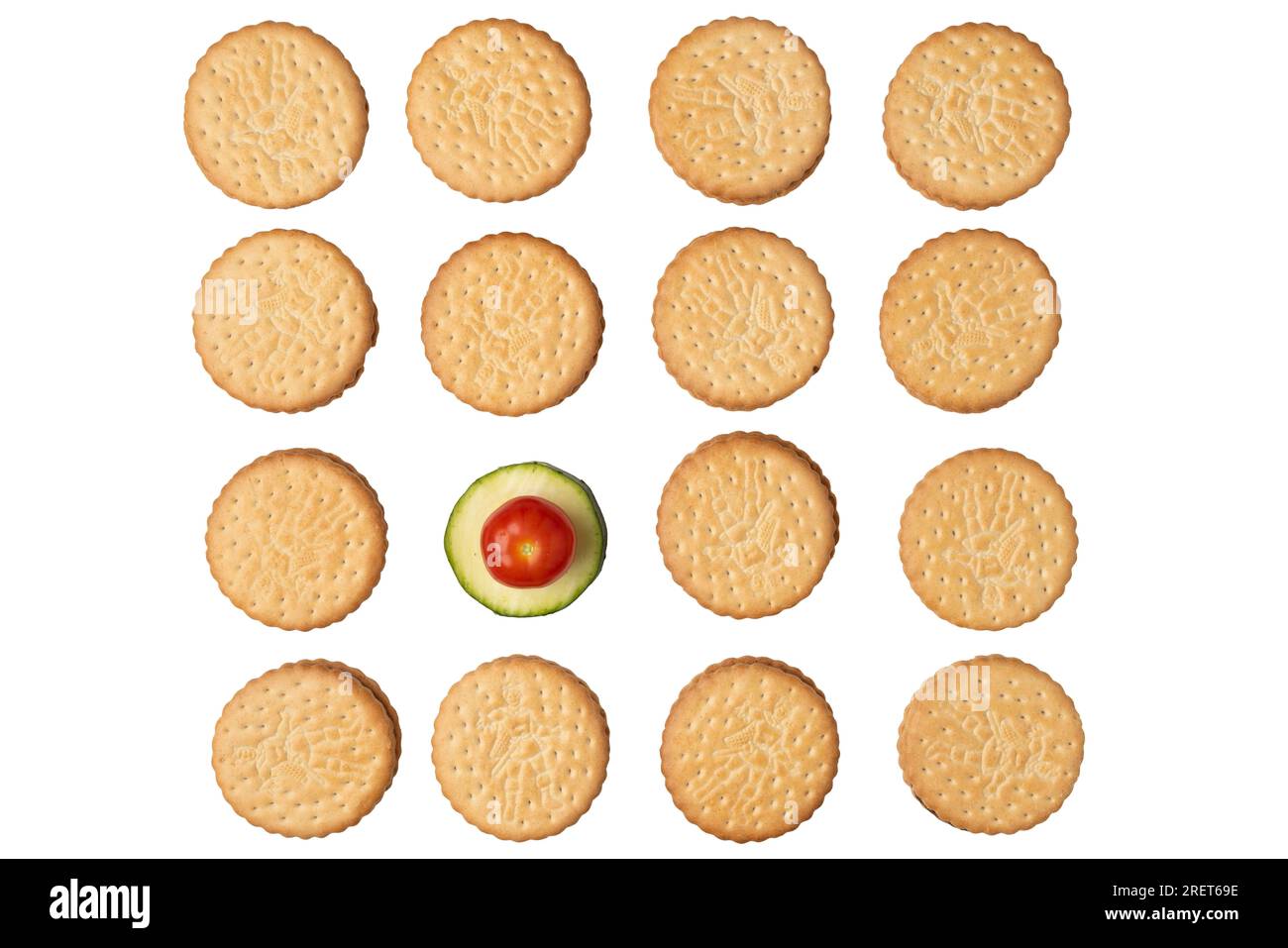 Double biscuits in rows with a courgette slice (Cucurbita pepo) and a tomato (Solanum lycopersicum), on white Stock Photo