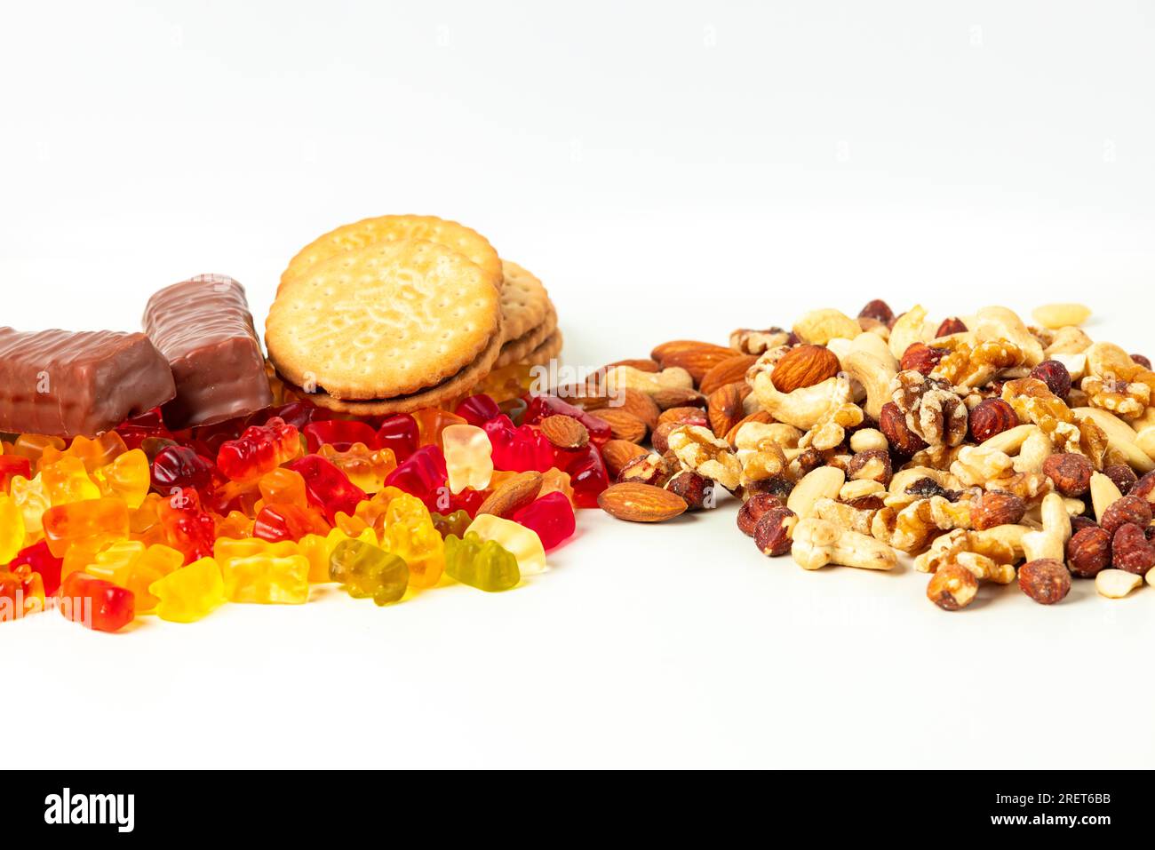 Gummi bears, biscuits and chocolate bars, next to various nuts, on