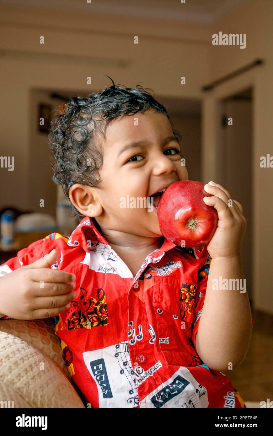 A south Indian 18 months old toddler boy Ashwin biting apple, Karnataka