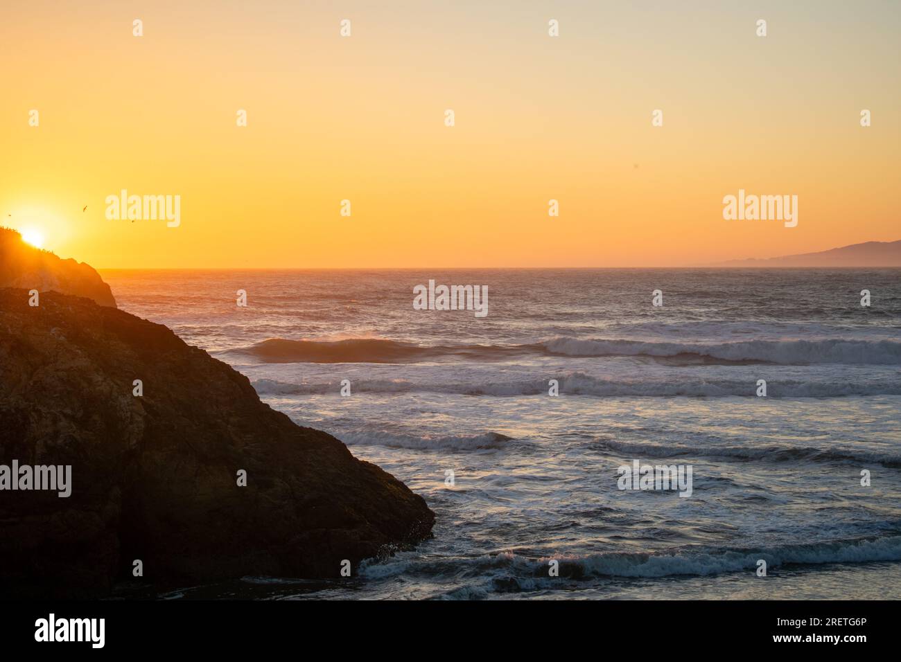 Serene sunset over the tranquil ocean, casting a golden glow. Stock Photo