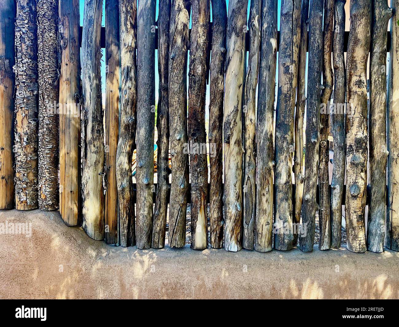 Taos, New Mexico, USA - July 23, 2023: Close-up of a traditional wood fence on an adobe wall common throughout northern New Mexico. Stock Photo