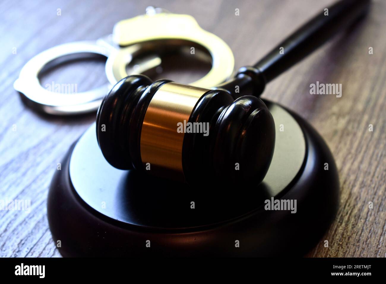 Judge’s gavel and block with handcuffs on a dark wooden table Stock Photo